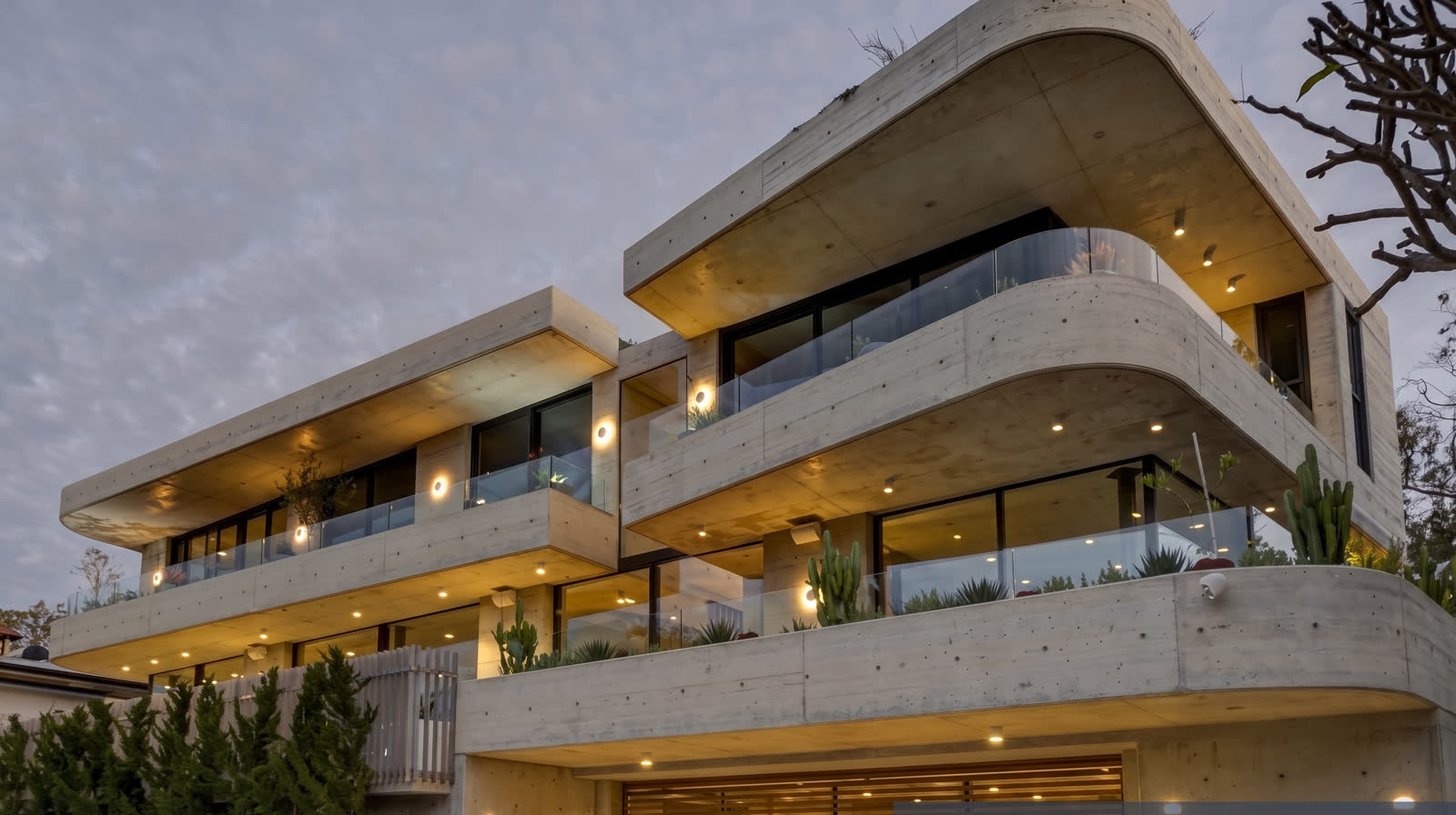 Curved off-form concrete facade at dusk with lit balconies, Bronte award house
