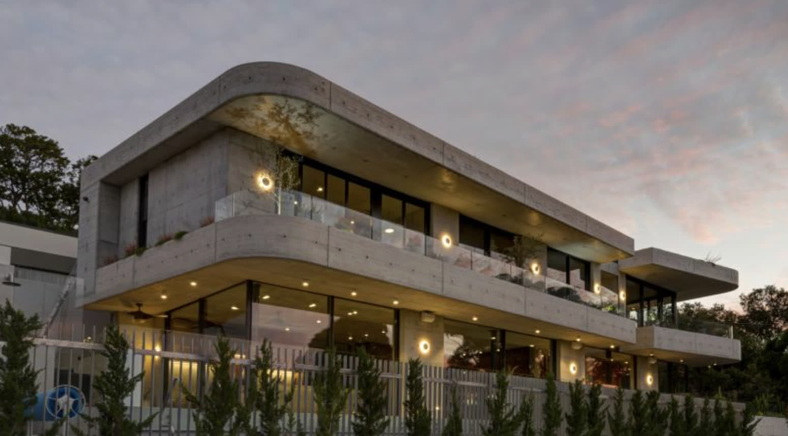 27 Evans Street, Bronte at dusk: the built off-form concrete house with stacked terraces and glass balustrades