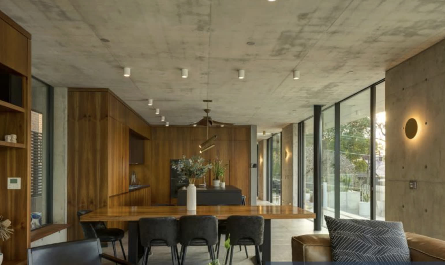 Open-plan living and dining with board-formed concrete, full-height glazing and timber joinery by Tillow Built.