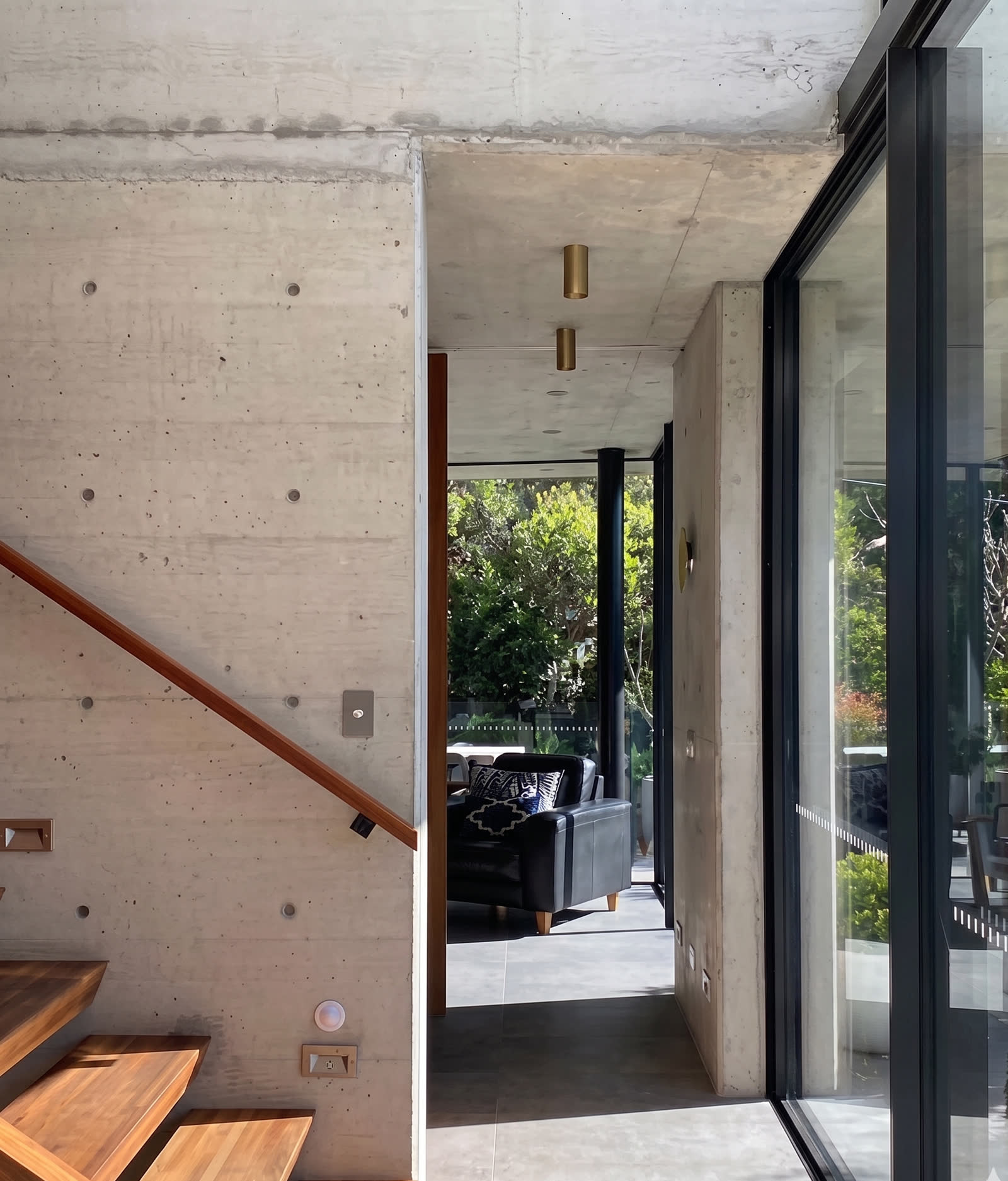 Entry hall with off-form concrete, timber stair and garden view through full-height glazing, Bronte award house